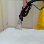 This is a photo of a man steam cleaning a dirty mattress.